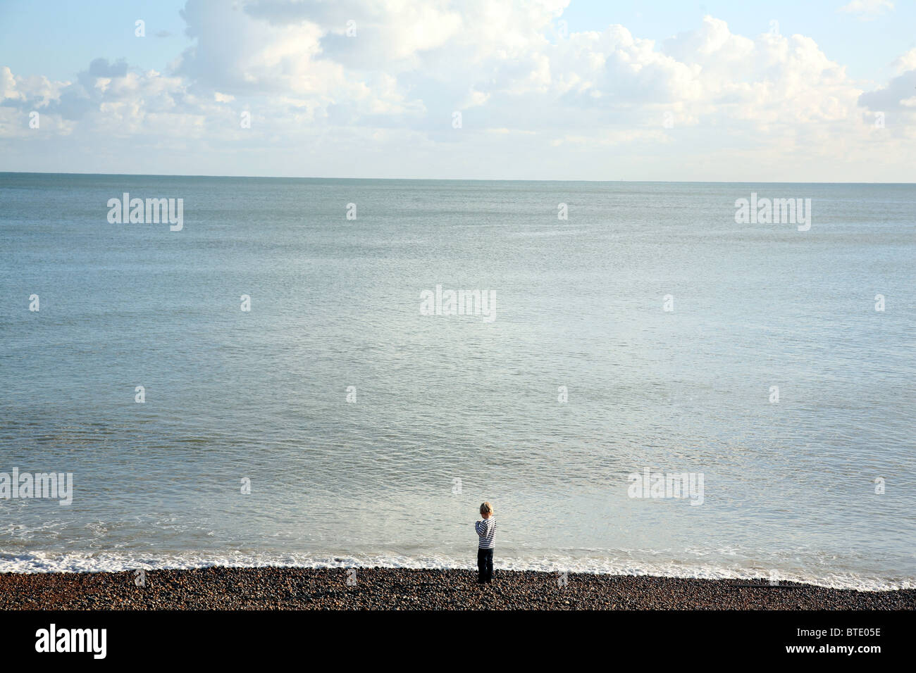 Petit garçon en haut breton contre l'immensité de l'océan, hastings, Sussex, England, UK Banque D'Images