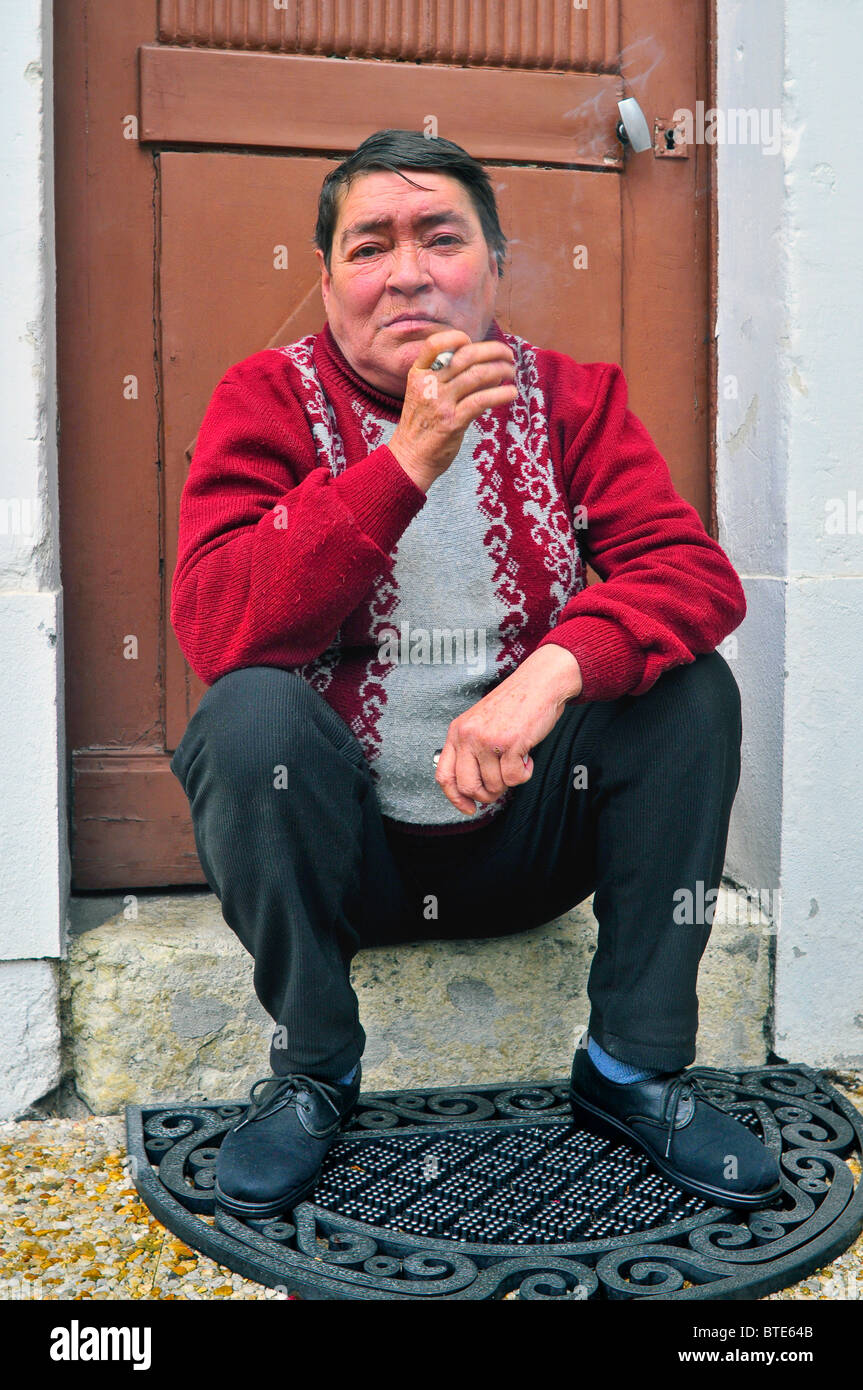 Vieille Femme assis sur porte de fumer - France. Banque D'Images