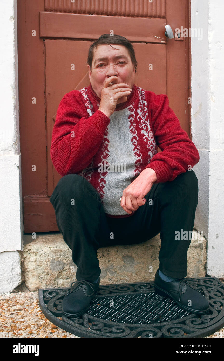 Vieille Femme assis sur porte de fumer - France. Banque D'Images