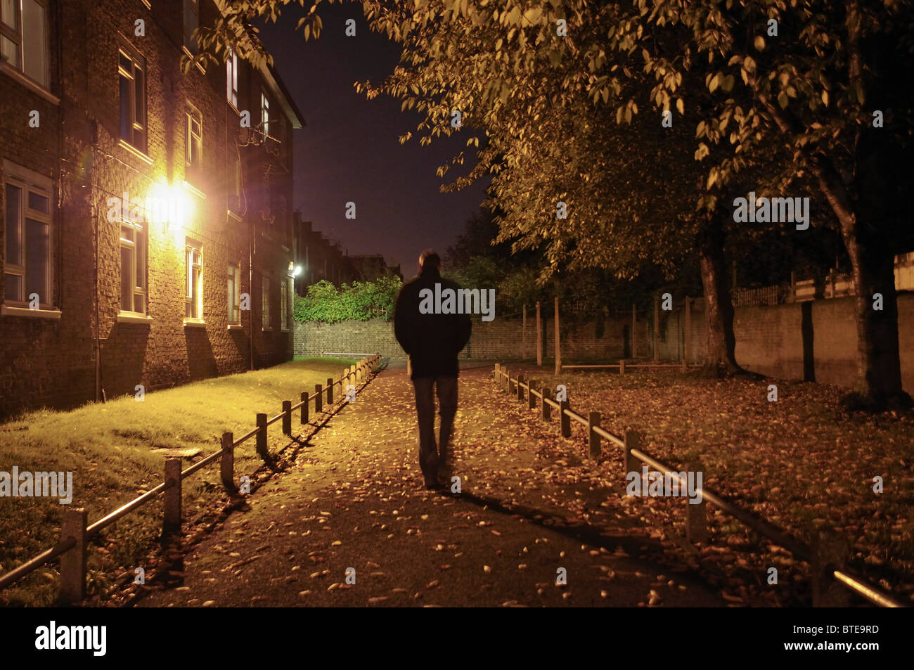 Homme marchant le long lane la nuit Banque D'Images