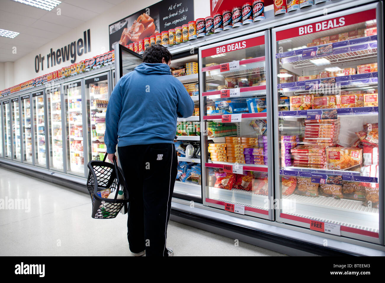 Un homme à la recherche d'un article dans la section d'aliments surgelés de Supermarché Coop, UK Banque D'Images
