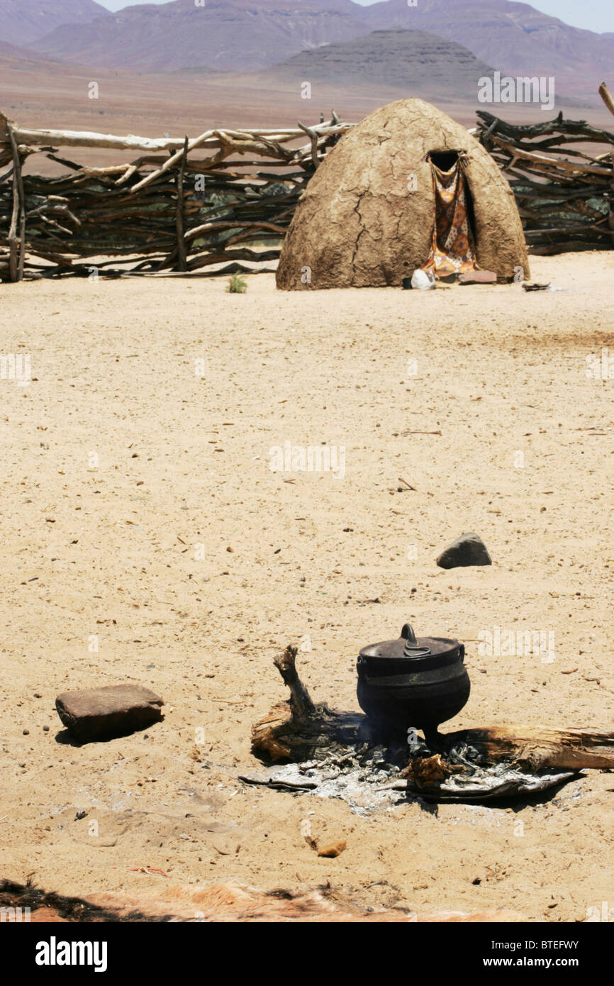 Pot à trois pieds au-dessus de cendres et d'une hutte Himba en arrière-plan Banque D'Images