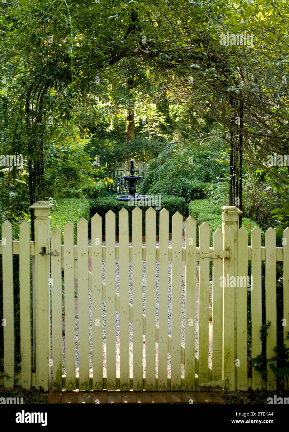 La porte de piquetage et trellis bienvenue au visiteur de ce jardin. Banque D'Images