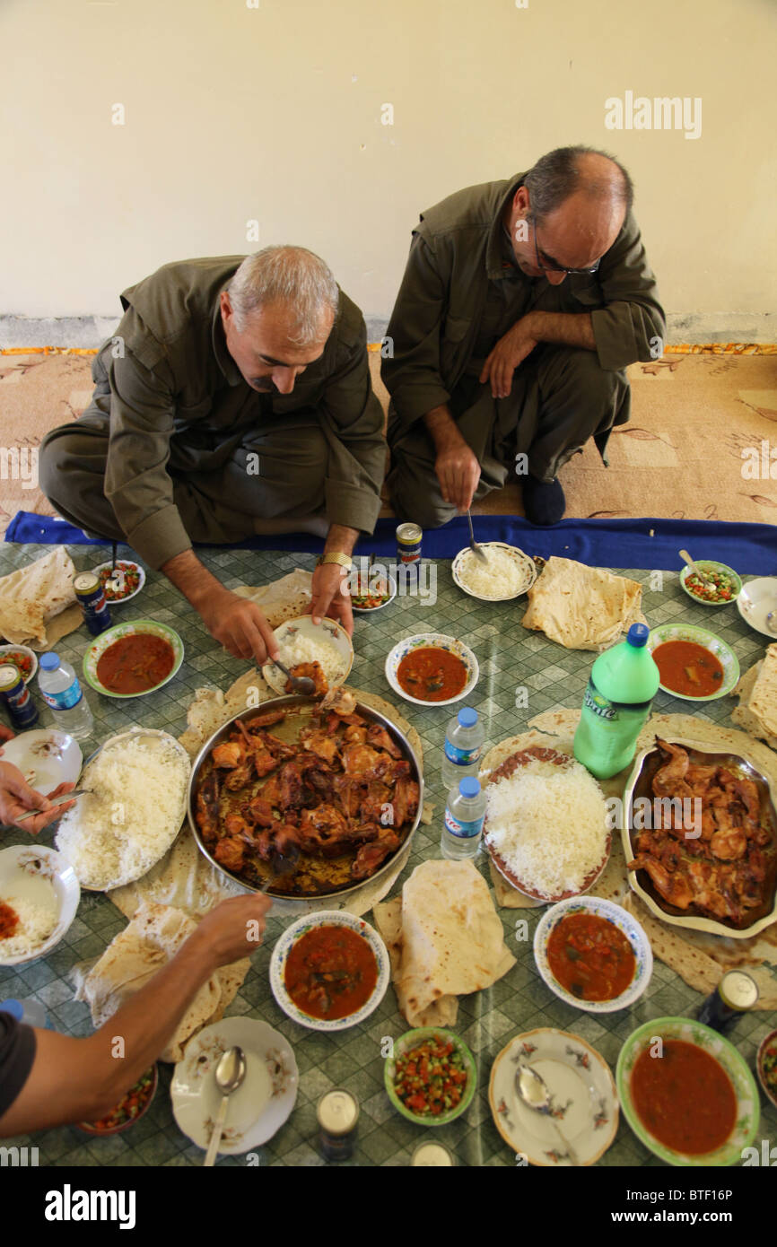 Un groupe de combattants kurdes des forces de défense populaires HPG, l'aile militaire du PKK du Parti des travailleurs du Kurdistan, mangeant de la nourriture traditionnelle kurde dans une maison sûre dans un village rural dans les montagnes de Qandil, une zone montagneuse près de la frontière avec l'Iran en Irak Banque D'Images