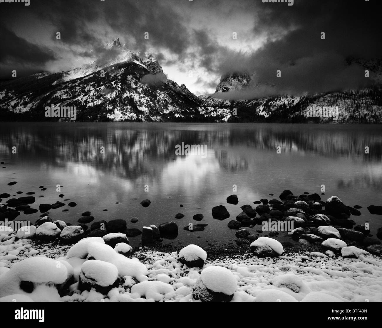 Un lever de réflexion sur un lac gelé Jenny montre première lumière grâce à une tempête hivernale dans la région de Parc National de Grand Teton, Wyoming. Banque D'Images