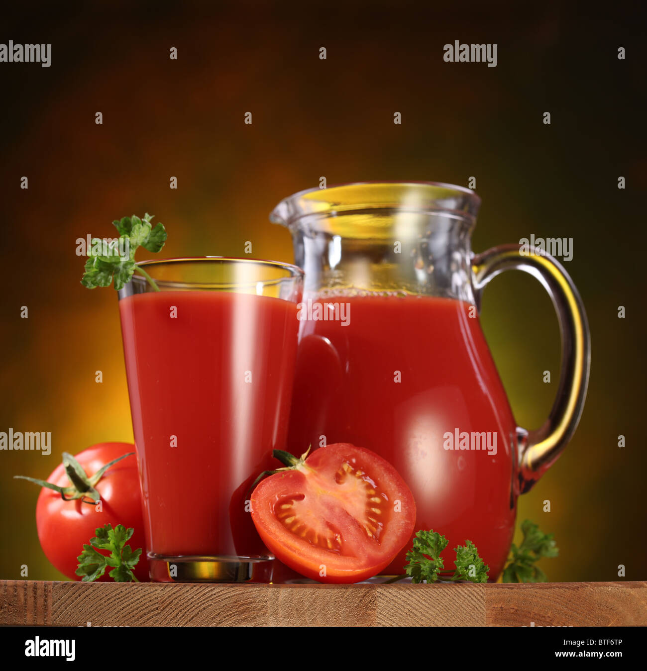 Still Life : tomates, verseuse en verre et plein de jus de tomates fraîches sur la table en bois. Banque D'Images