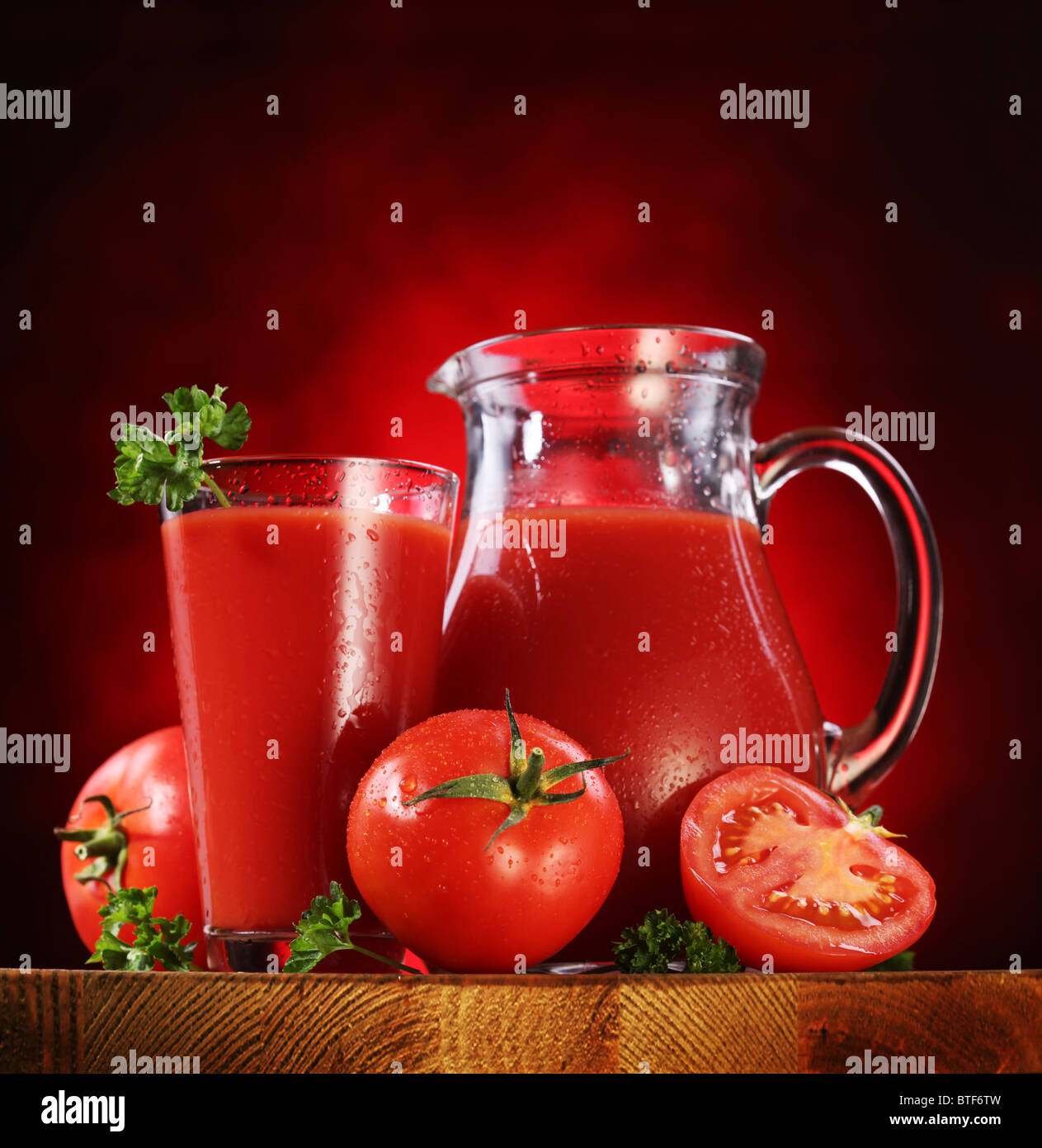Still Life : tomates, verseuse en verre et plein de jus de tomates fraîches sur la table en bois. Banque D'Images