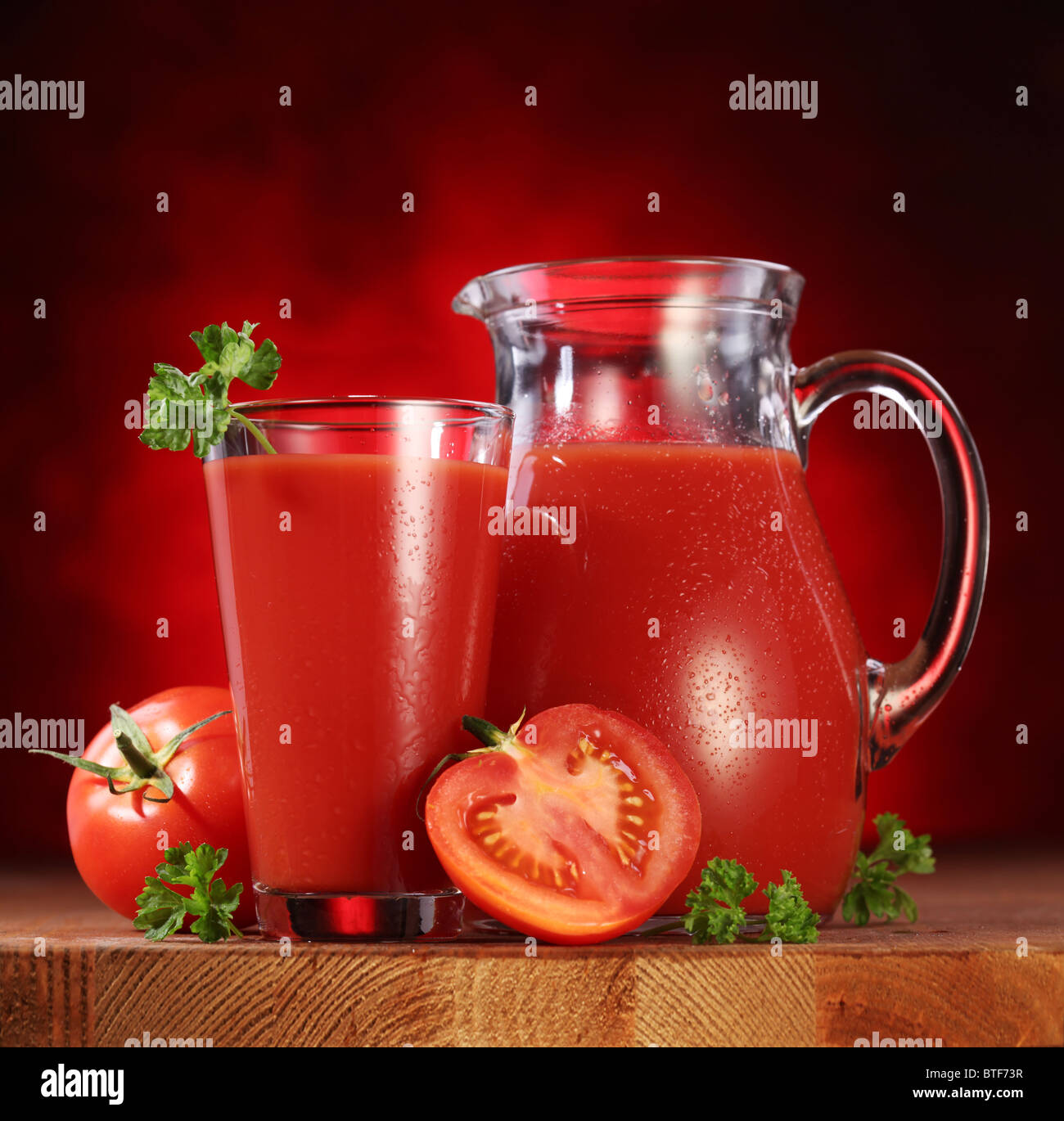 Still Life : tomates, verseuse en verre et plein de jus de tomates fraîches sur la table en bois. Banque D'Images