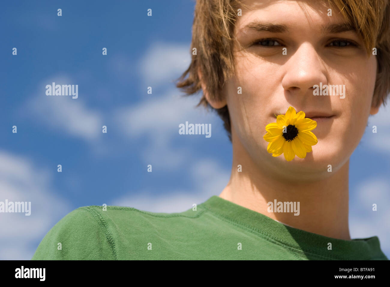 Jeune homme à la fleur dans la bouche, portrait Banque D'Images