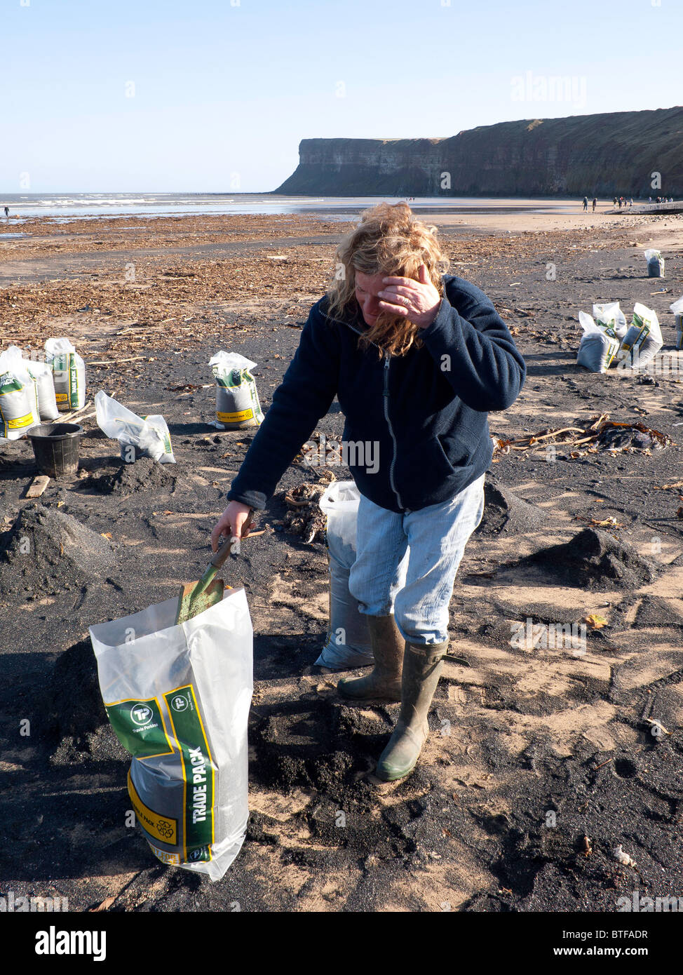 Une femme la collecte du charbon de la mer sur la plage pour brûler dans l'incendie domestique une tradition locale dans la région de Angleterre du Nord-Est Banque D'Images