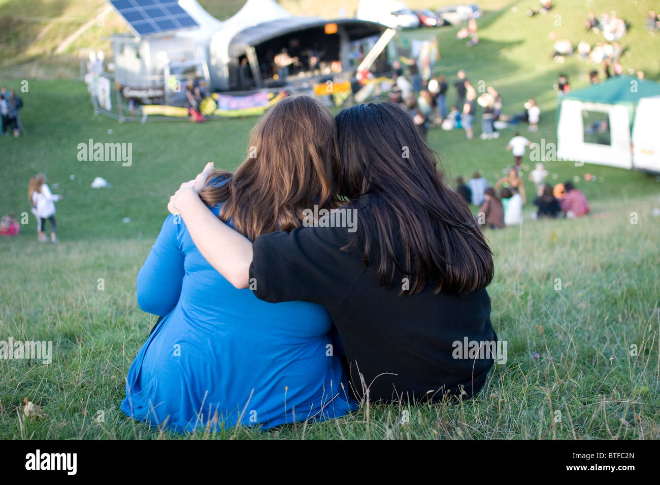 Un couple d'amoureux de la musique aux cheveux longs s'asseoir près de la scène principale en Carshalton Park pendant la Foire de l'environnement, 2010. Banque D'Images