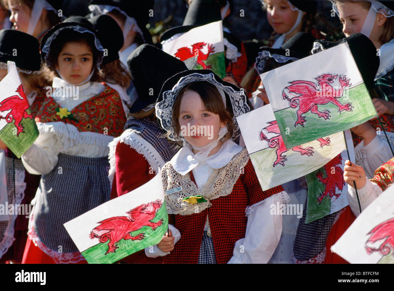 Welsh enfants habillés en costume national avec dragon rouge drapeaux gallois pour St David's day celebration, Pays de Galles, Royaume-Uni Banque D'Images