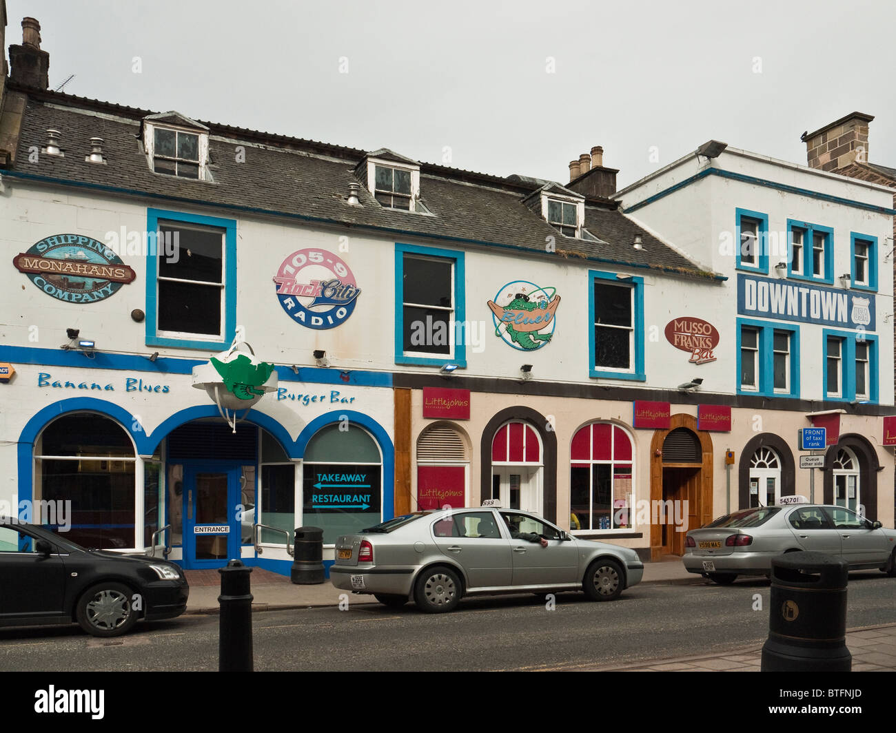 Rangée d'entreprises peint de couleurs vives : Monahans, Rock City Radio, LittleJohns, centre-ville de USA club, High Street, Elgin, Ecosse, Royaume-Uni Banque D'Images