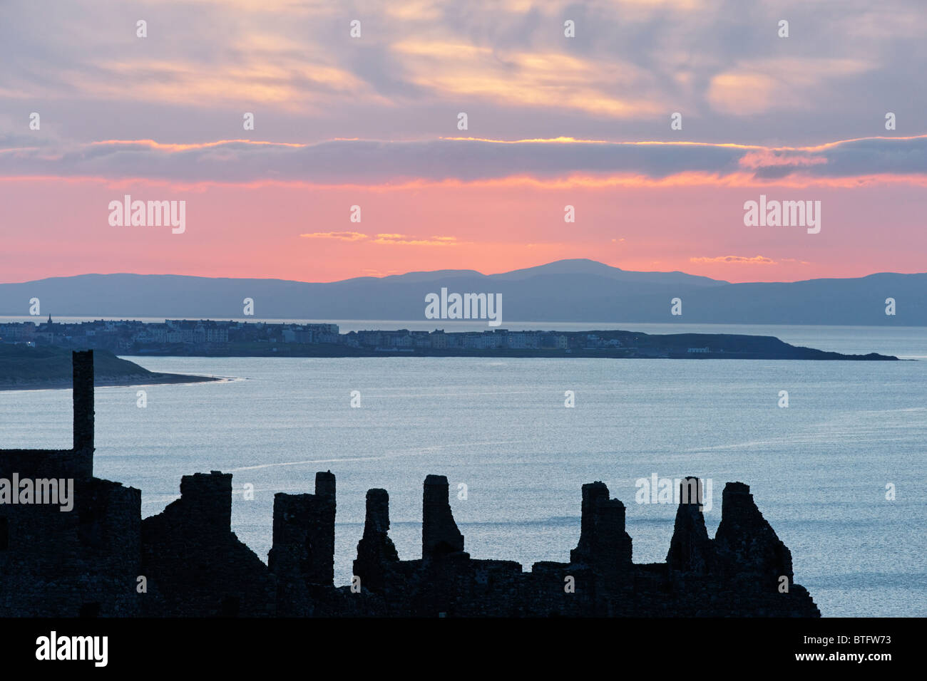 Le Château de Dunluce, comté d'Antrim, l'Ulster (Irlande du Nord, Royaume-Uni. Silhouette de ruines au coucher du soleil. Banque D'Images