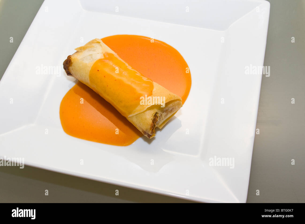 Rouleaux de crêpes avec une sauce aigre-douce sur une plaque blanche Banque D'Images