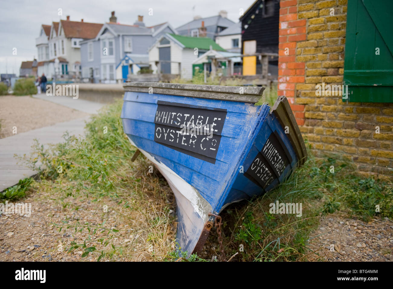 Un bateau à rames en bois la publicité Whitstable Oyster Company sur la plage sur Whitstable Banque D'Images