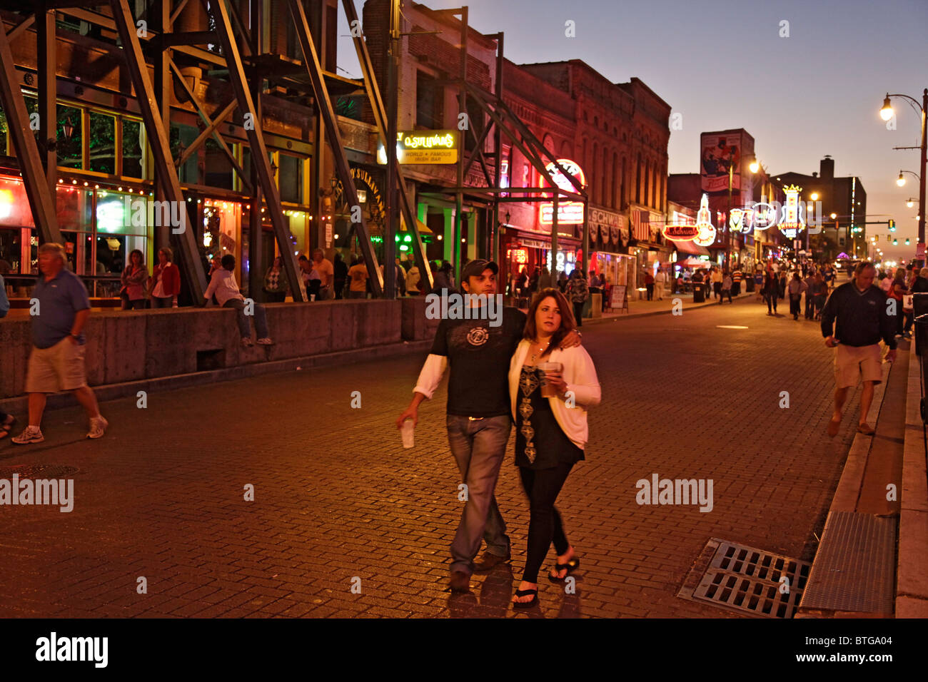 Jeune couple à l'avant-plan de Beale Streetm centre-ville de Memphis, Tennessee, USA un vendredi soir en octobre. Banque D'Images