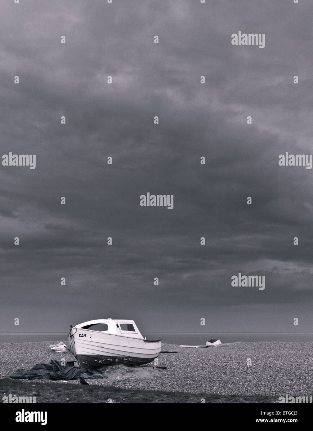 Image Monochrome d'un petit bateau de pêche sur la plage de Hunstanton avec un ciel dramatique derrière Banque D'Images