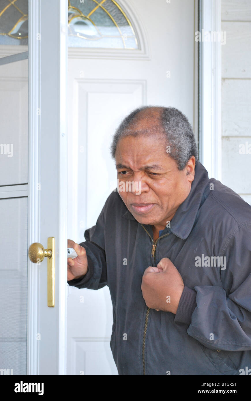 African American man avoir une crise cardiaque tout en laissant sa maison. Banque D'Images