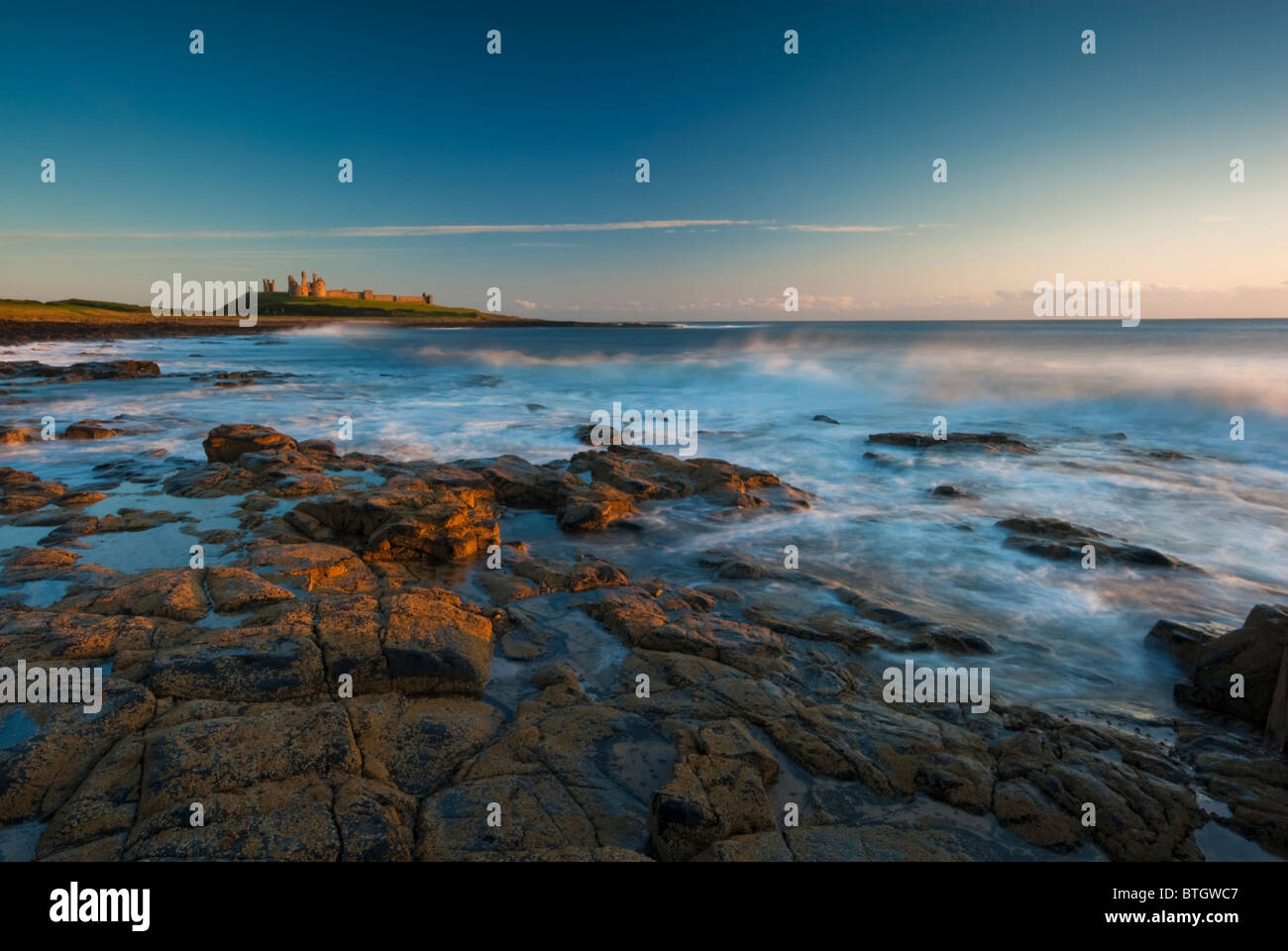 Château de Dunstanburgh sur la côte de Northumberland à l'aube Banque D'Images