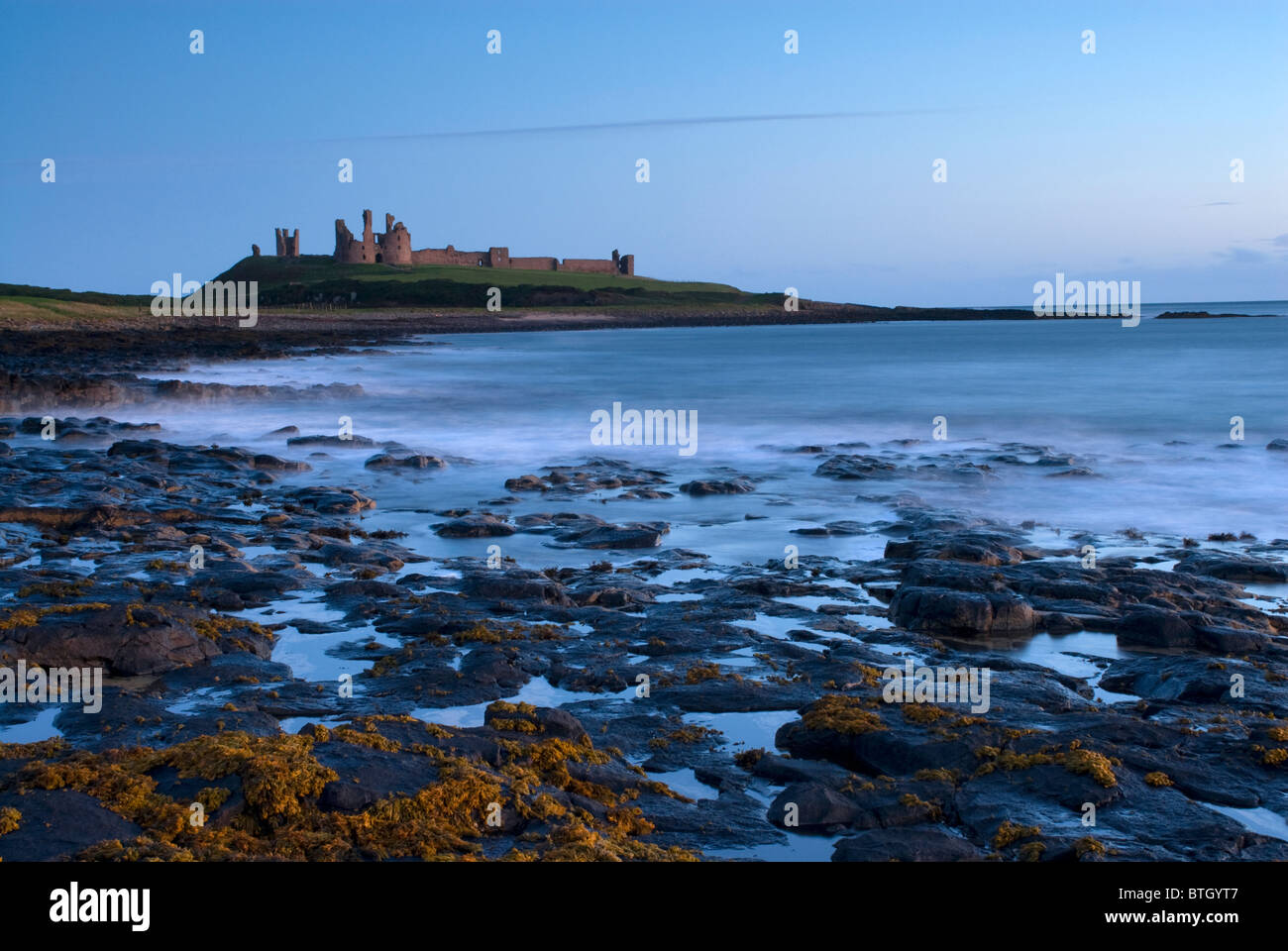 Château de Dunstanburgh sur la côte de Northumberland à l'aube Banque D'Images