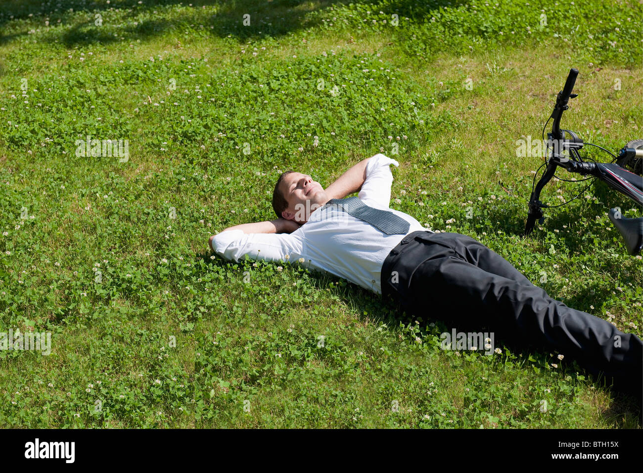 Businessman couché dans l'herbe à côté de location de profiter du soleil Banque D'Images