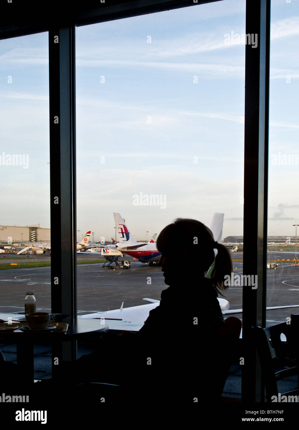 La silhouette d'une femme assise dans un bar d'aéroport. Banque D'Images