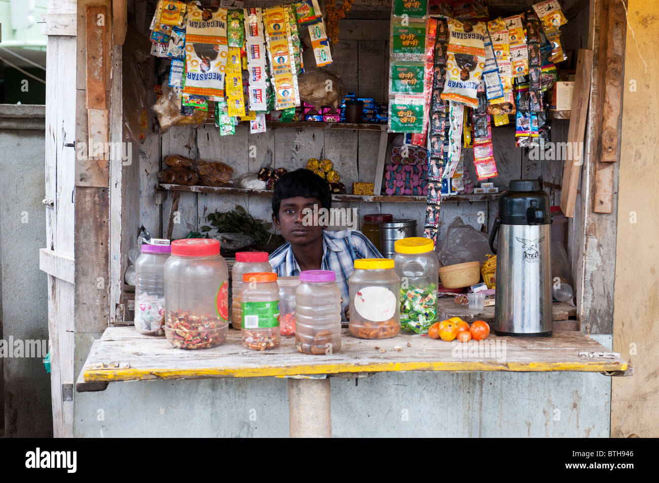Village indien garçon vente d'articles de boutique / stall à Puttaparthi, Andhra Pradesh, Inde Banque D'Images
