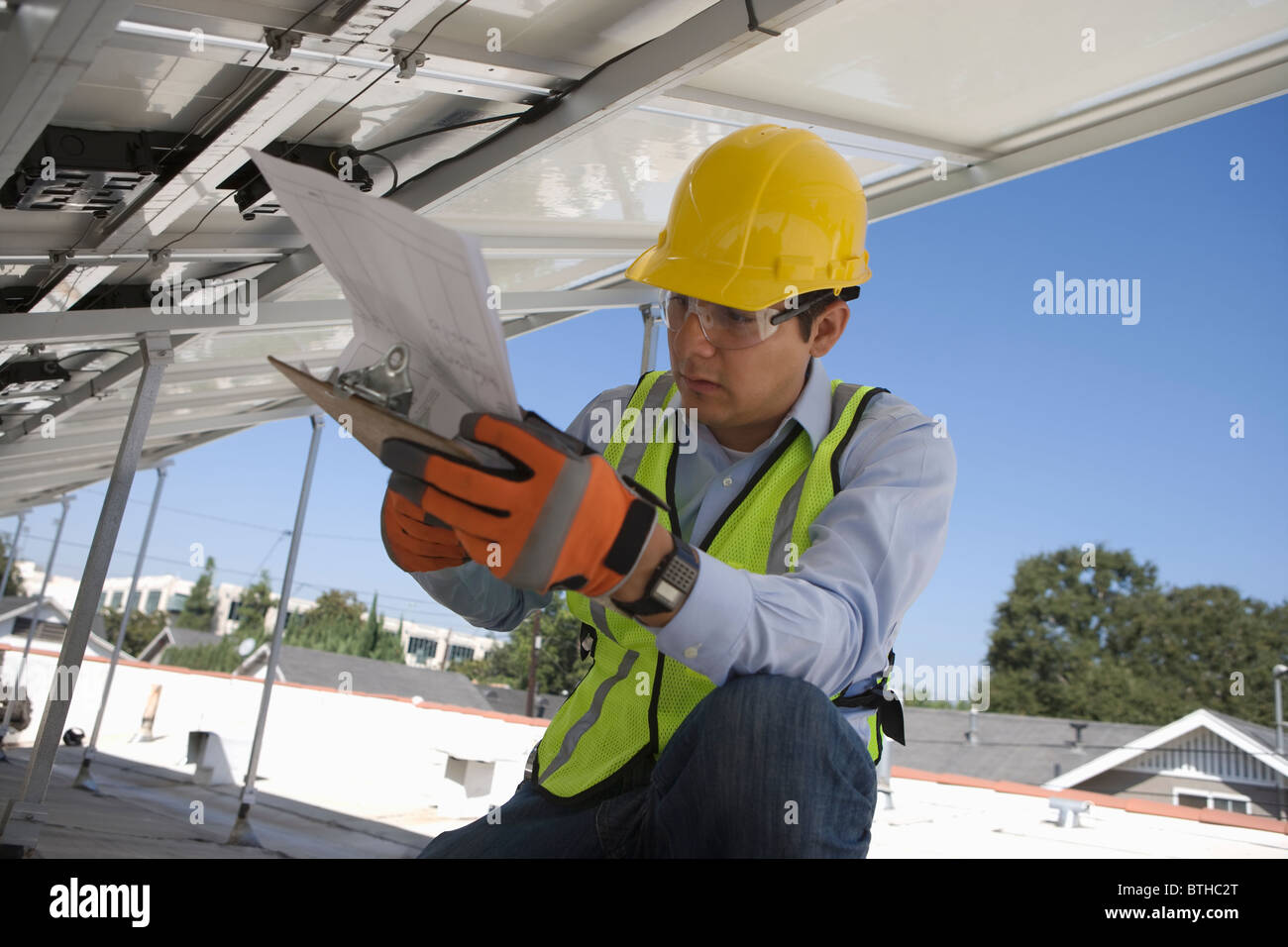 Ouvrier d'entretien fait référence à des billets en vertu de panneau solaire à Los Angeles, Californie Banque D'Images