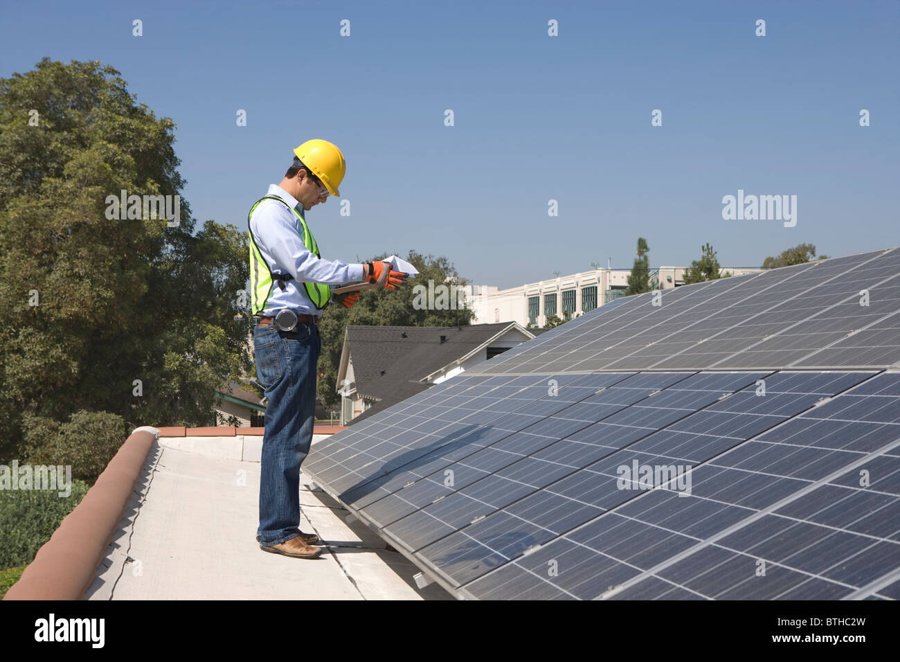 Ouvrier d'entretien se distingue avec batterie solaire sur toit, Los Angeles, Californie Banque D'Images