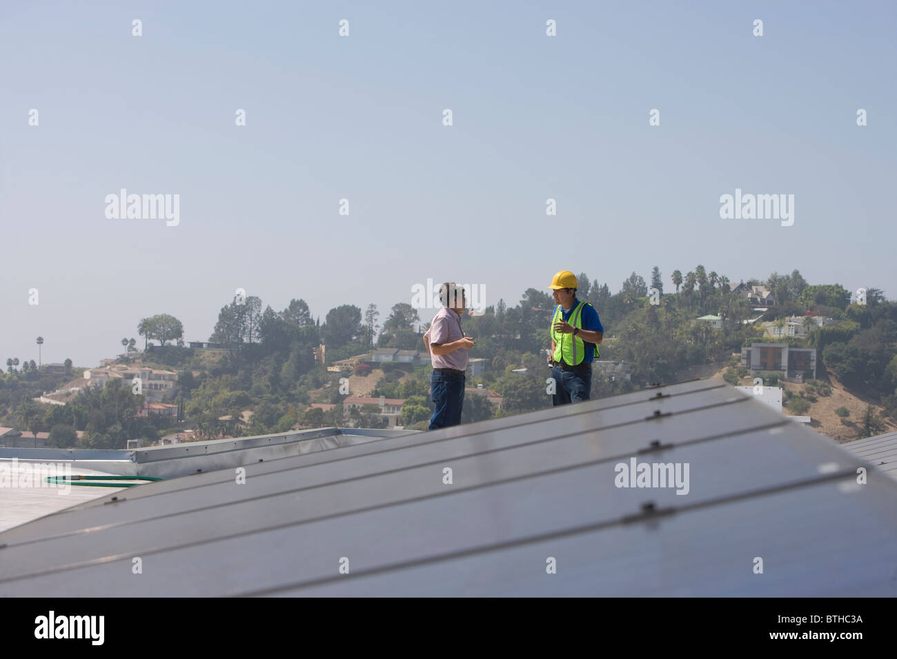 Les travailleurs d'entretien support avec batterie solaire sur toit à Los Angeles, Californie Banque D'Images