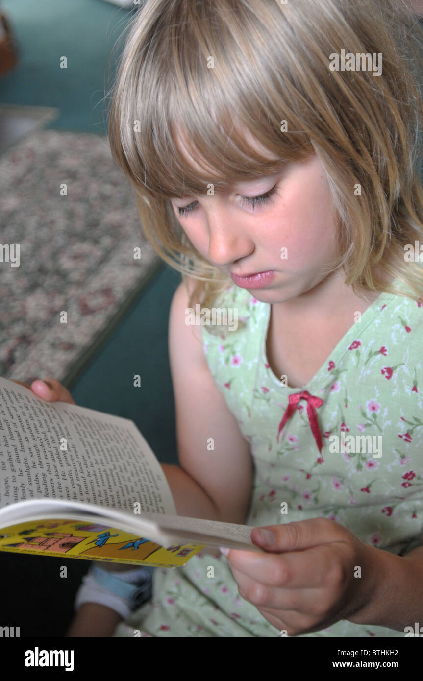 Une fillette de 8 ans la lecture dans son salon. Banque D'Images