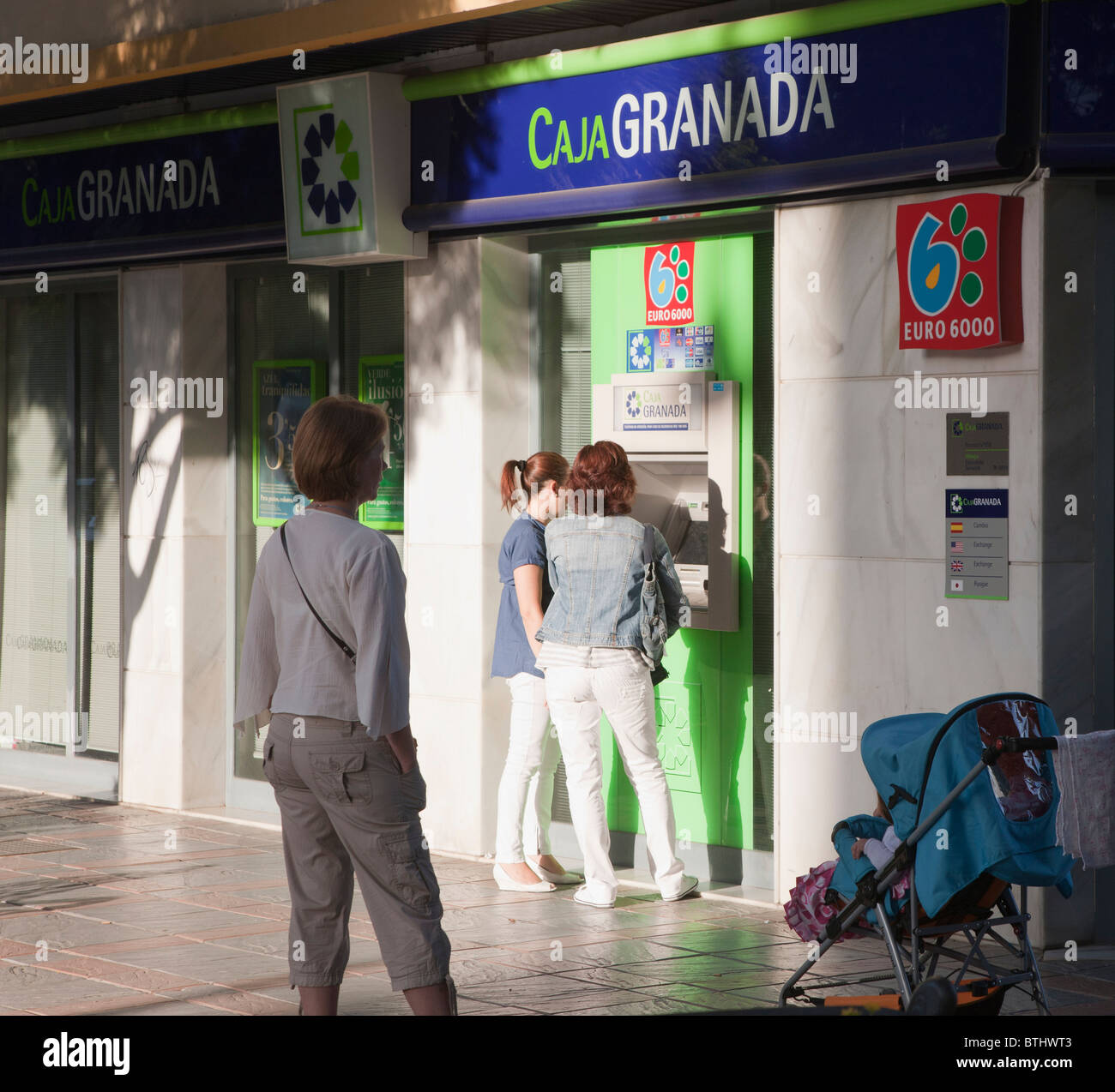 Clients qui prennent de l'argent d'argent comptant hors de Caja Granada en direction de Fuengirola, province de Malaga, Costa del Sol, Espagne. Banque D'Images