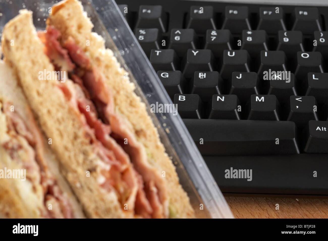 Triple à emporter sandwiches dans le carton à côté de clavier de l'ordinateur à l'heure du déjeuner Banque D'Images