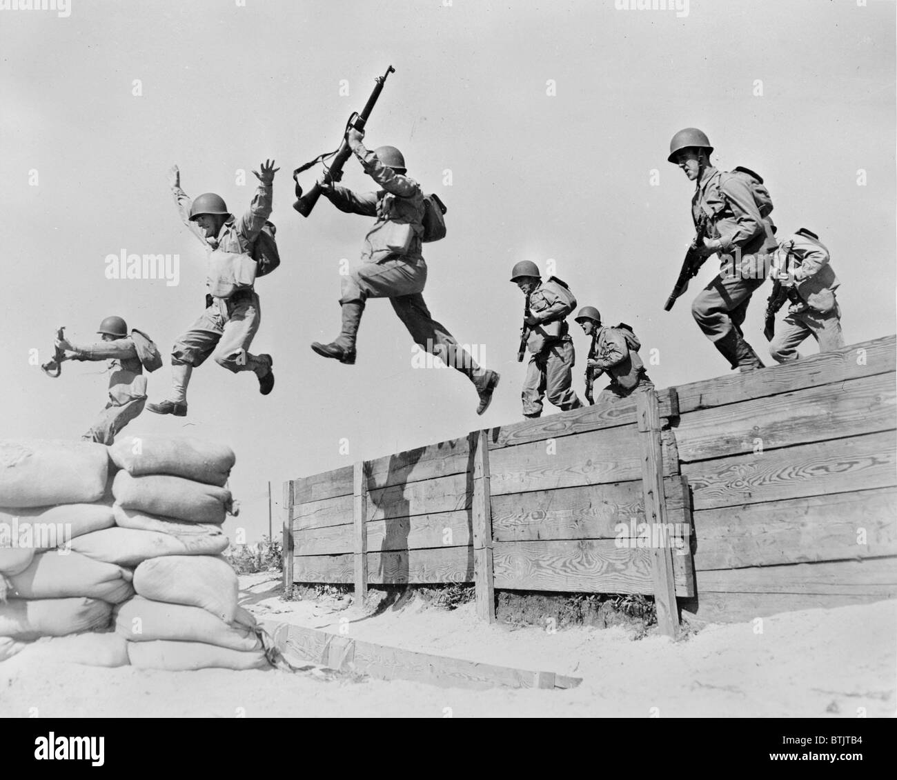 La Seconde Guerre mondiale, légende originale : Un disque-exécutant leap prend ces artilleurs sur l'un des obstacles sur le parcours au centre de formation anti-aériens. Nous voyons ici les différentes phases du saut ; un homme a tout juste de se poser sur le sable ; deux sont dans l'air ; et un autre homme est lui-même la collecte pour l'ensemble de printemps", Camp Edwards, Massachusetts, 1942. Banque D'Images