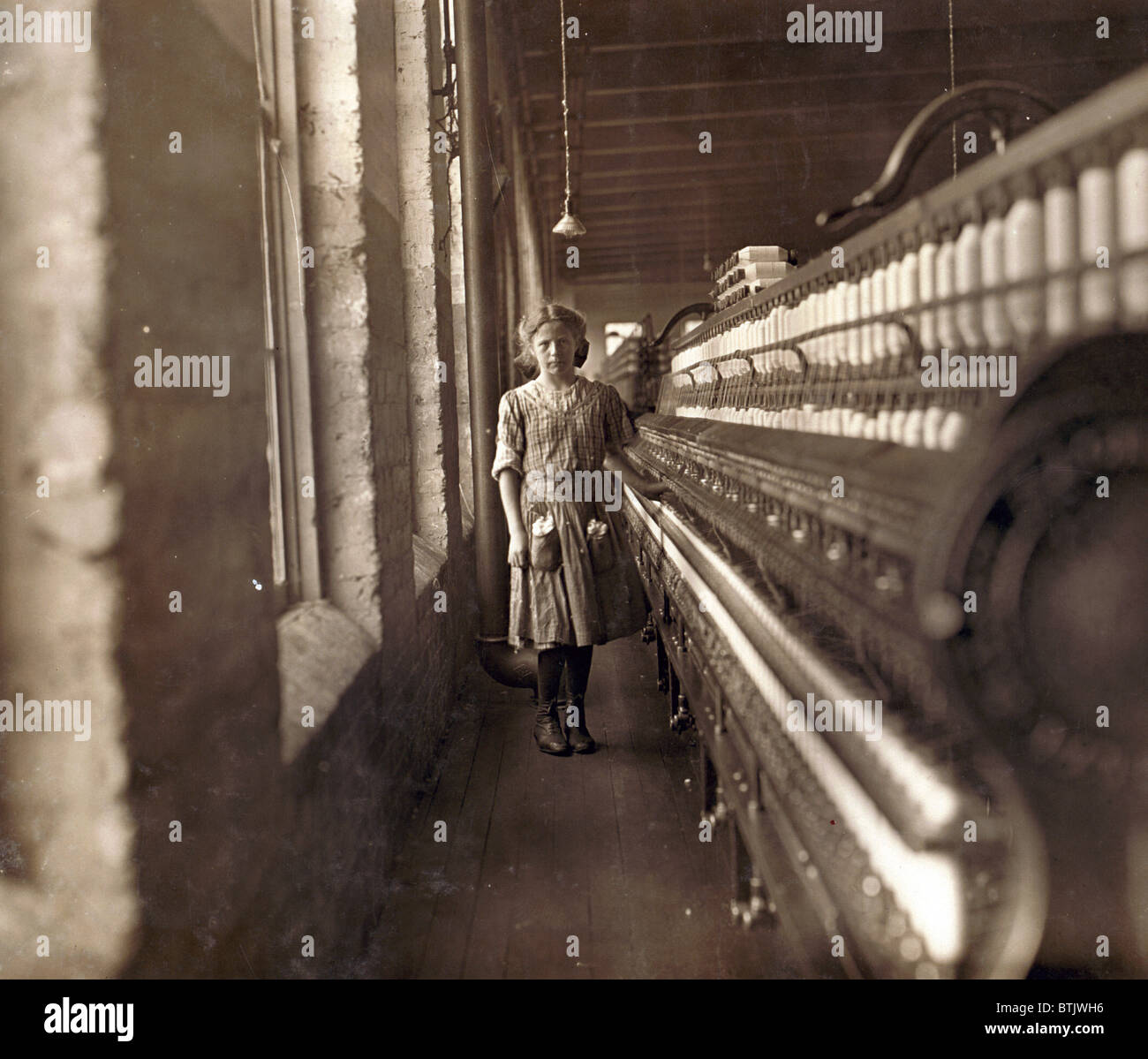 Cotton Mill. Une jeune fille mineure tend un fileur de coton . Daniel, Lincolnton, Caroline du Nord. Photo par Lewis Wickes Hine, Banque D'Images