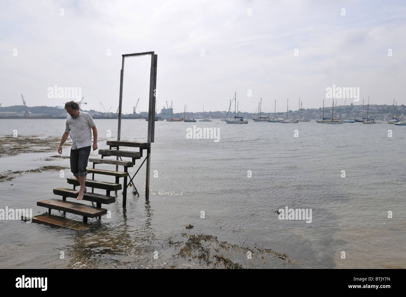 Un homme marche le long de certaines étapes dans la mer Banque D'Images