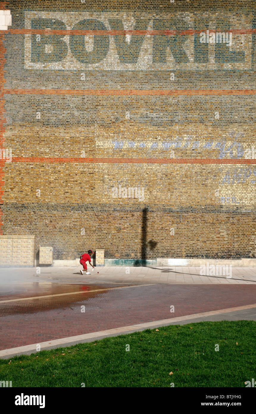 Petit garçon frapper une balle contre le "Mur des Bovril sur Windrush Square, Brixton, London, UK Banque D'Images