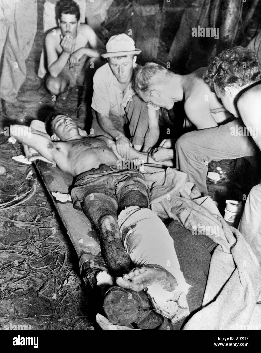 La transfusion sanguine. Un soldat américain blessé reçoit une transfusion de sang tandis que sur l'engin stationnaire assistants lit bébé. La scène est 'Somewhere en Guinée', 1943-1945 Banque D'Images