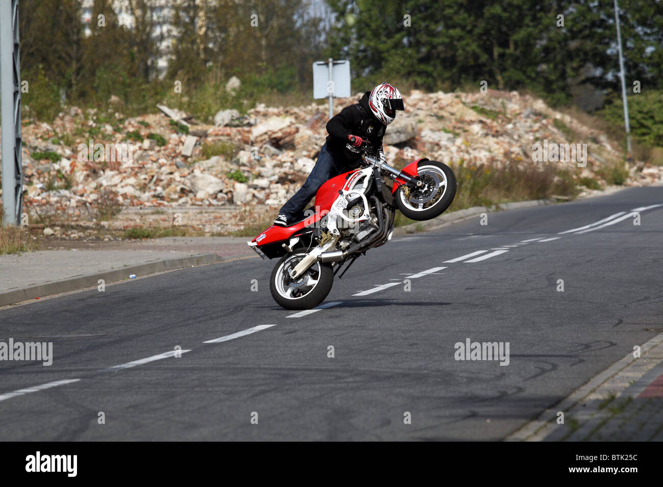 Stunt motorbiker en équilibre sur sa Honda moto sur roue arrière. Banque D'Images