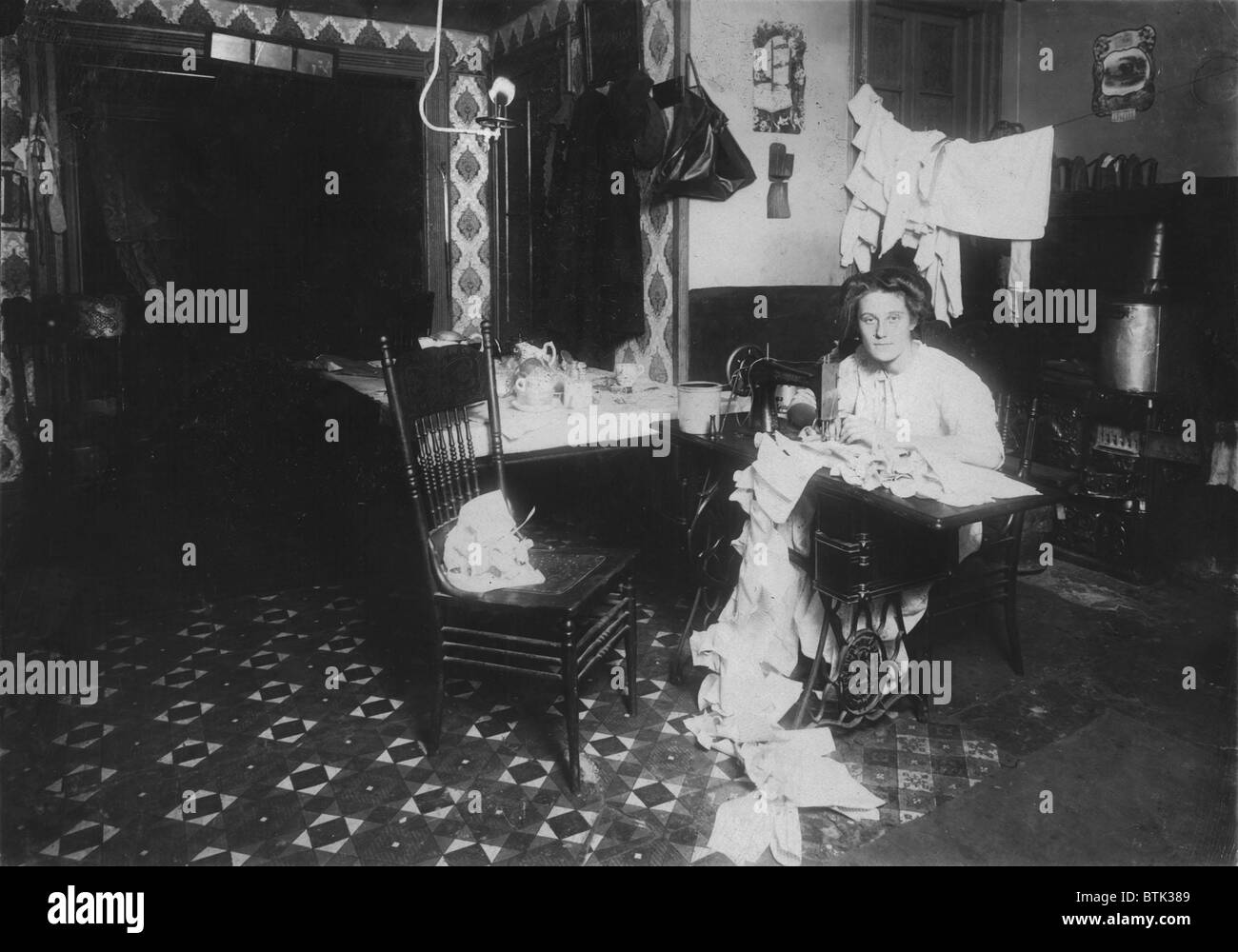 Femme travaillant en sous-sol, à partir de la légende : "Annie Maier (ou Meyer), faisant de Campbell-kids' pinafores dans son sous-sol à la maison. 71 E. 108 Rue. Elle aurait la tuberculose. Travailler dans la cuisine.', New York, photo de Lewis Wickes Hine, Décembre, 1911 Banque D'Images