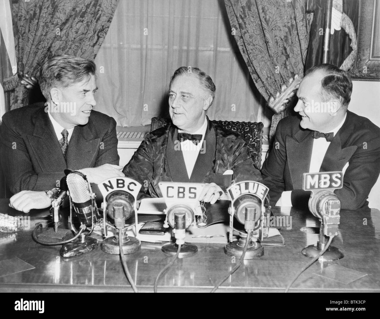 Vice-président Henry A. Wallace, le président Franklin D. Roosevelt, et secrétaire de l'Agriculture Claude Wickard, à de micros pour une émission de radio contre l'inflation. Wallace suppose la gestion de l'économie de guerre. Banque D'Images