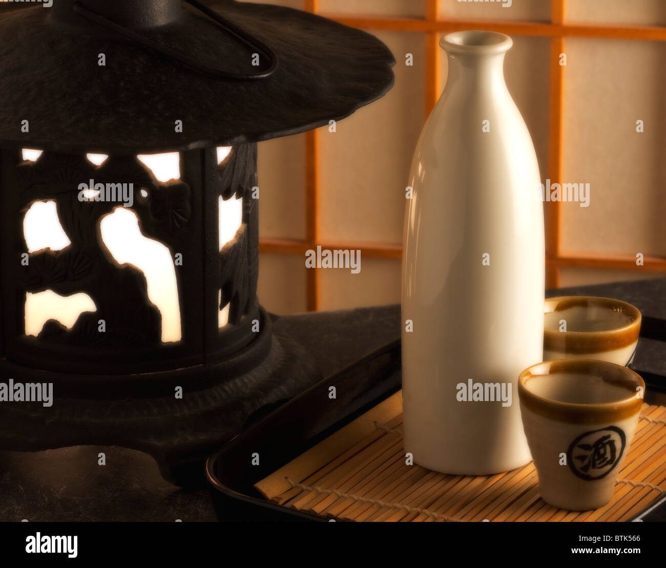 Bouteille de sake japonais et deux tasses à côté d'une lanterne en fonte Banque D'Images