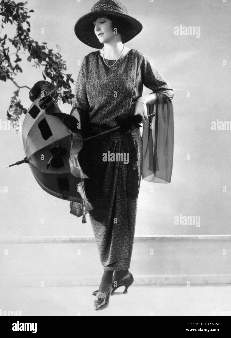 Robe d'après-midi de faille imprimé avec chapeau et parasol pour le début du printemps 1923. Photo : Courtesy Everett Collection Banque D'Images