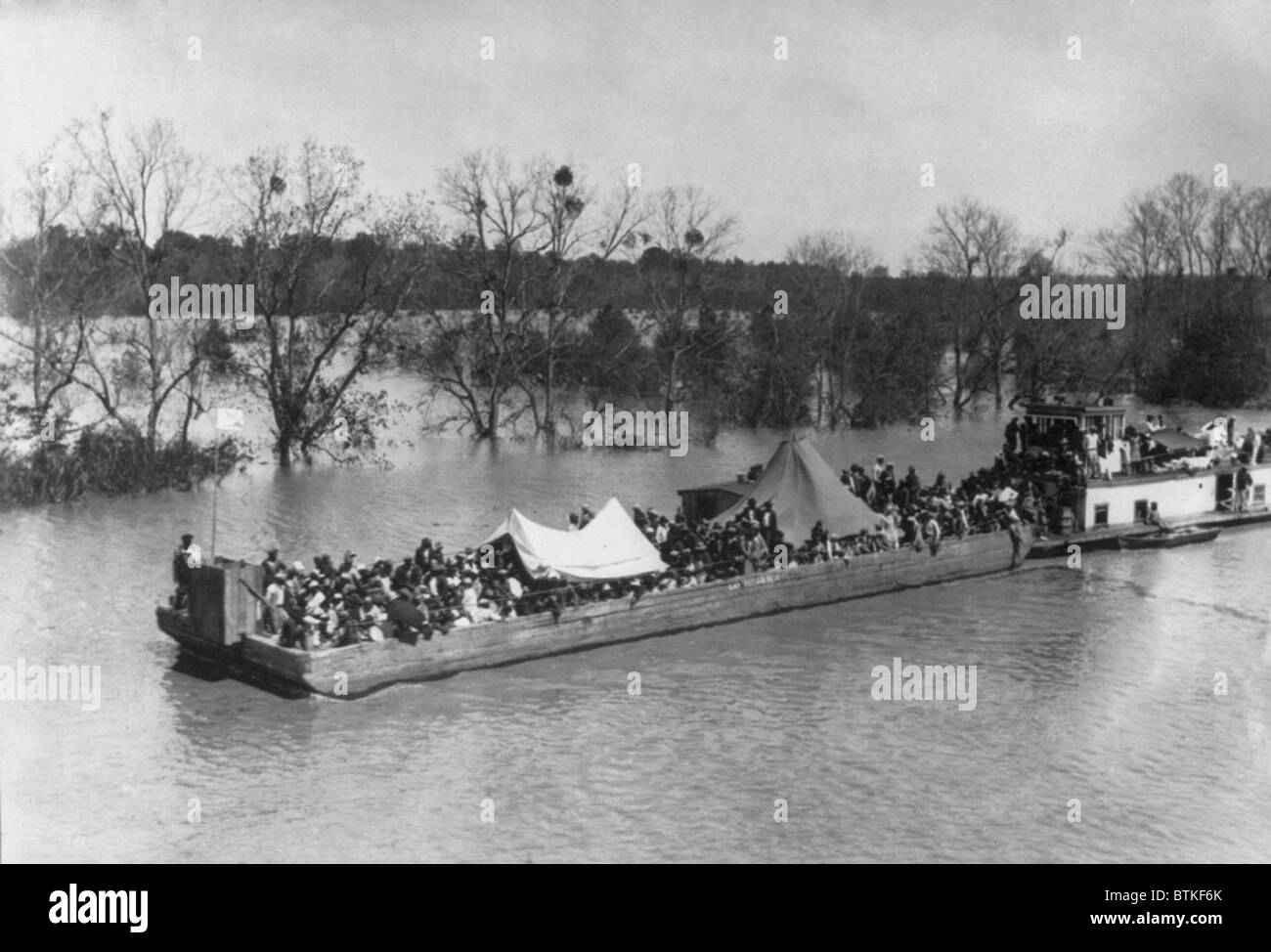 Chaland chargé avec les réfugiés africains pauvres sur la rivière de tournesol dans le Mississippi au cours de l'inondation de 1927. Les responsables de secours n'ont pas évacuer les Africains américains sur les zones inondées dans la crainte de perdre des travailleurs des plantations, whowould ont peu d'incitations au retour au travail de terrain de coton à bas salaires. Banque D'Images