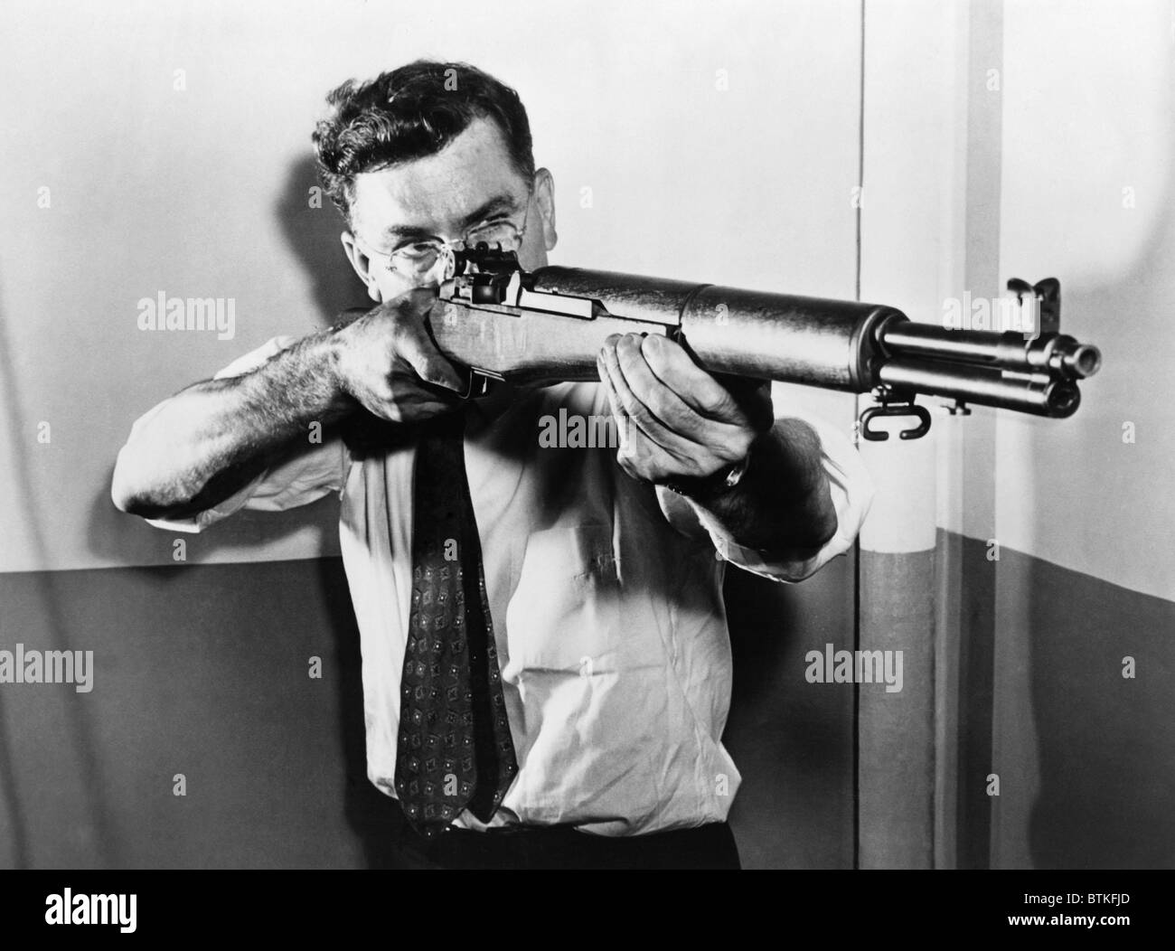 John C. Garand (1888-1974), visant l'un des fusils américains semi-automatique, le calibre .30 M 1, qu'il a inventé. La M1 carabine semi-automatique, a été utilisé par les fantassins américains pendant la Seconde Guerre mondiale et la guerre de Corée. Ca. 1943. Banque D'Images