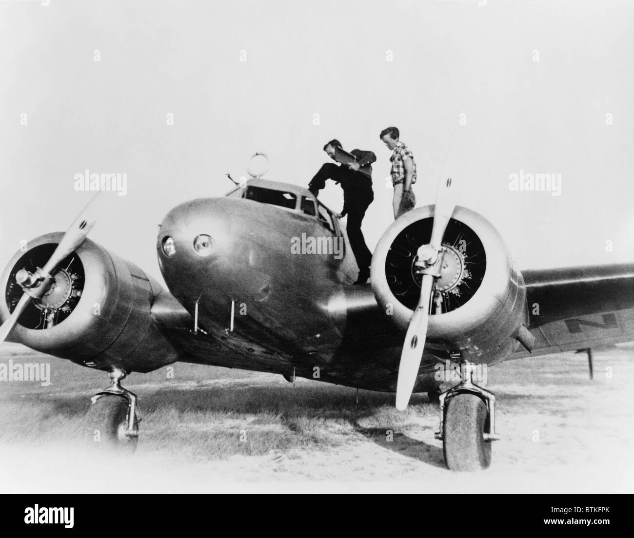 Amelia Earhart stanind sur l'aile de son Lockheed L-10E Electra avion. À la droite est Fred Noonan, son navigator entrant dans le cockpit, lors d'un arrêt à Porto Rico durant leur tentative de voler autour du monde. 1937. Banque D'Images