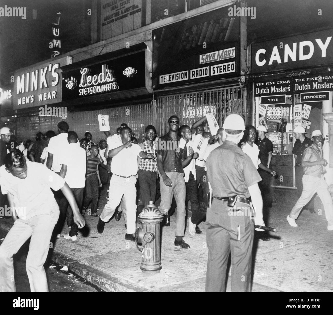 Jeune foule scandant le long du trottoir sur 125th St. pendant le premier des émeutes de 1960 à Harlem, New York City. Les 15 et 16 juillet 1964. Banque D'Images