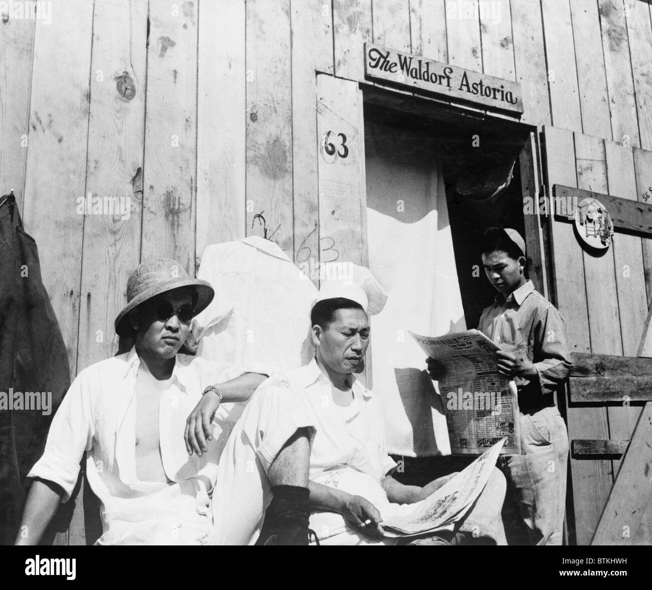 Les hommes japonais américain de Seattle, Washington s'asseoir à l'extérieur une caserne durant leur séjour de quatre mois à Puyallup Centre Assemblée générale en 1942. L'autorité désignée de réinstallation temporaire, l'internement de 'Camp Harmonie.' Les internés à son tour nommé leur caserne le 'w'. Banque D'Images