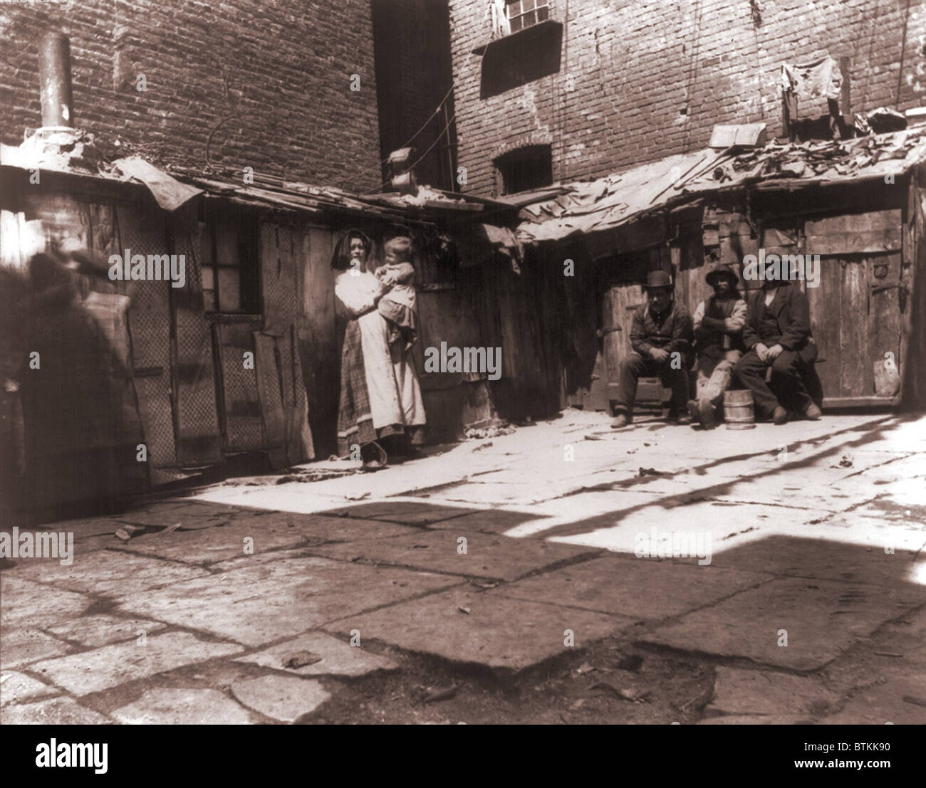 Cour pavée avec les lignes des latrines en plein air dans l'une des pires bidonvilles sur Jersey Street, où les pauvres italiens immigrants vivaient à New York. 1889 Photographie par Jacob Riis. Banque D'Images